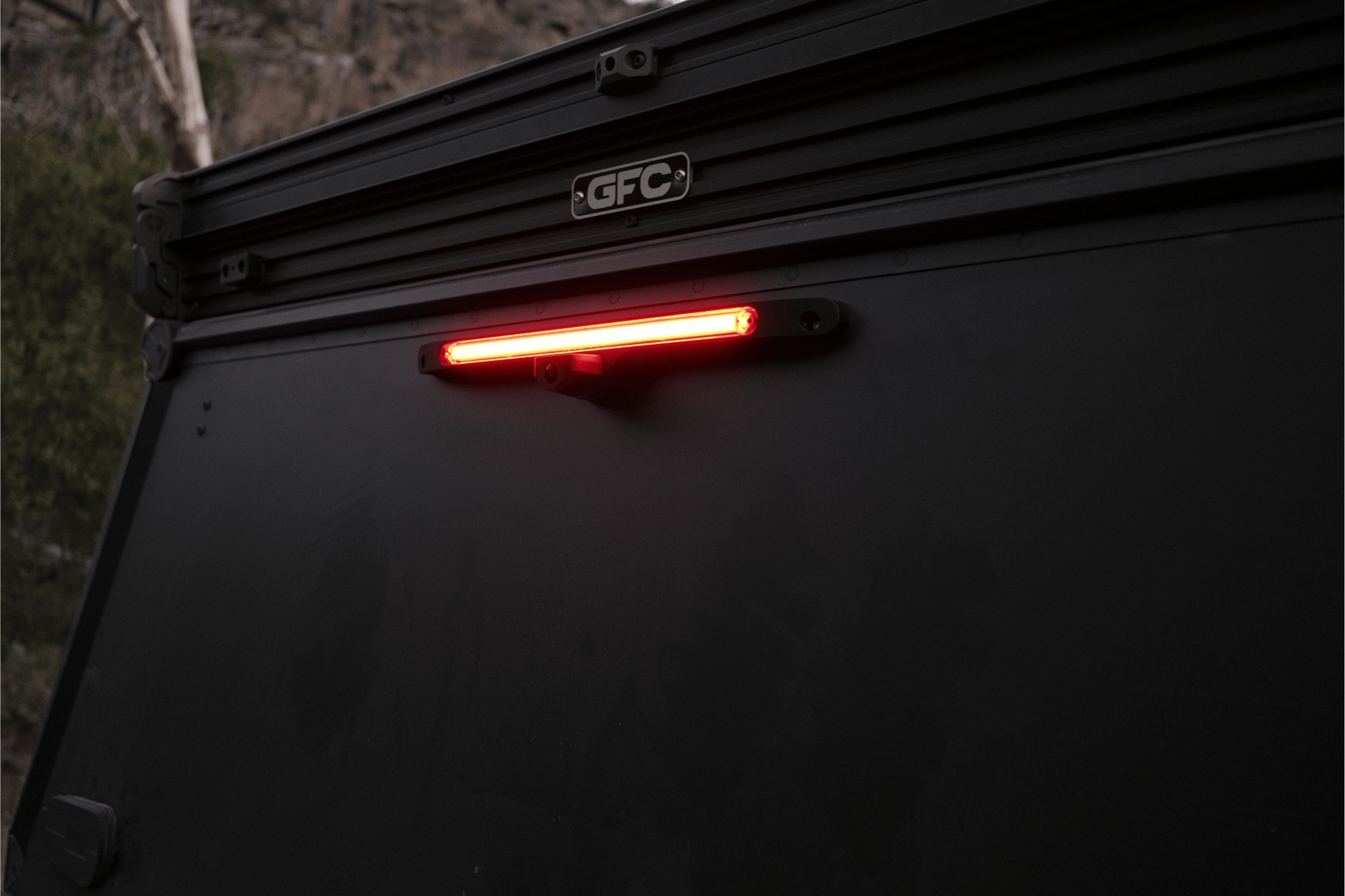 Tail light of a vehicle with 'GFC' branding in a dark setting