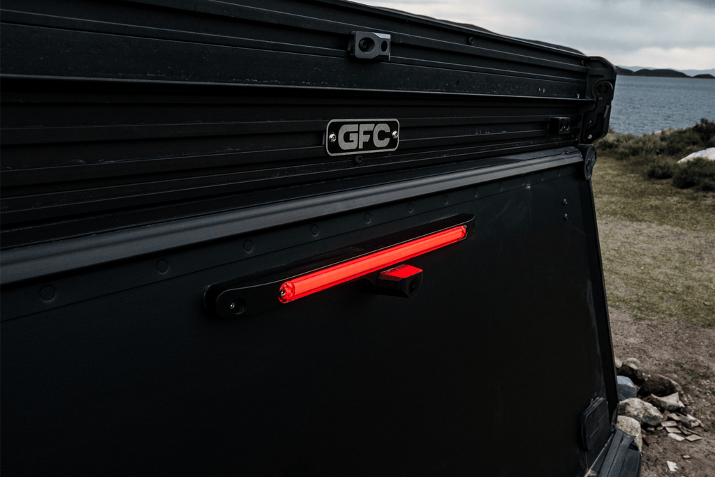 Black vehicle roof rack with red light and 'GFC' logo against a natural background