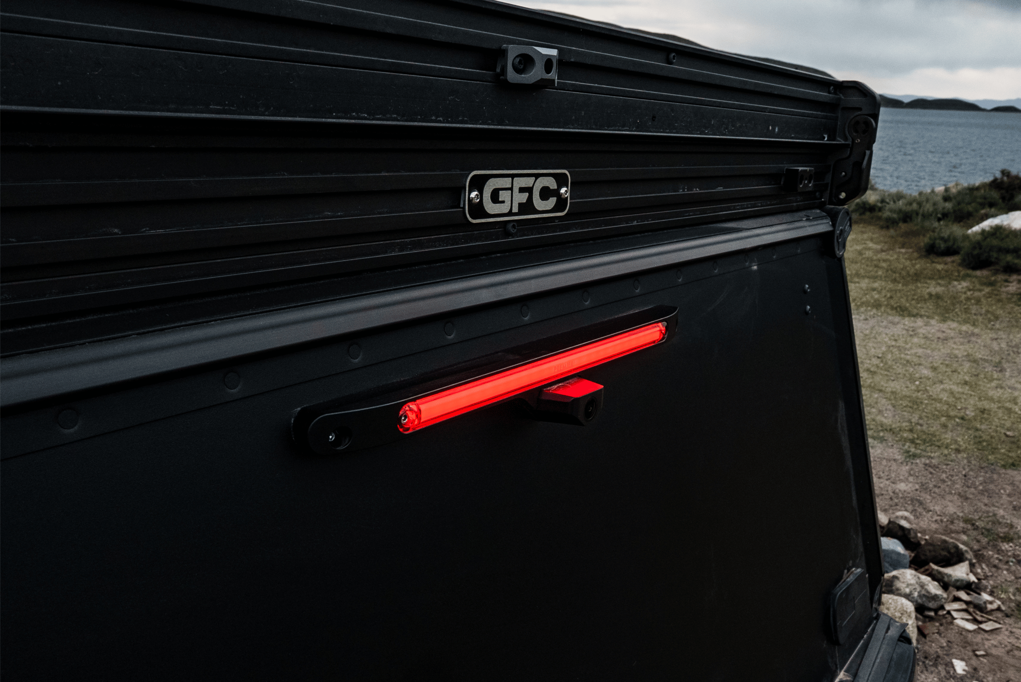 Black vehicle roof rack with red light and 'GFC' logo against a natural background
